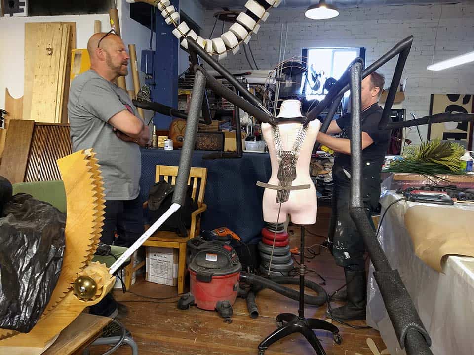 Crit Killen and Hraefn Wulfson with the welded steel shoulder frame and chassis for new custom mosquito mascot on a dress dummy the same size as performer